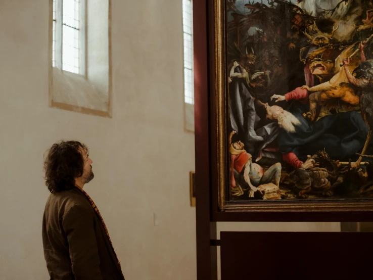 a man standing in front of a painting, inspired by Lorenzo Lotto, pexels contest winner, standing inside of a church, lucas cranach, looking around a corner, museum archive