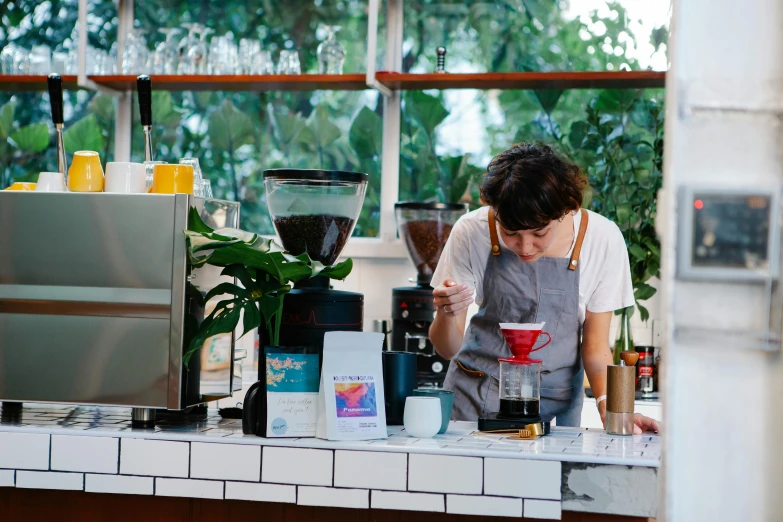 a person standing at a counter with a blender, by Julia Pishtar, pexels contest winner, aussie baristas, lush surroundings, avatar image, dripping blue natural iwakura