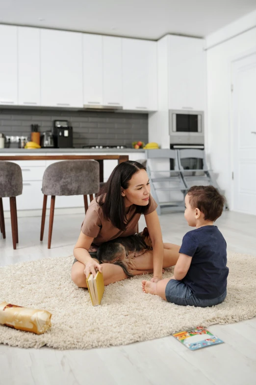 a woman and child sitting on a rug in a living room, in a kitchen, profile image, beige, dwell