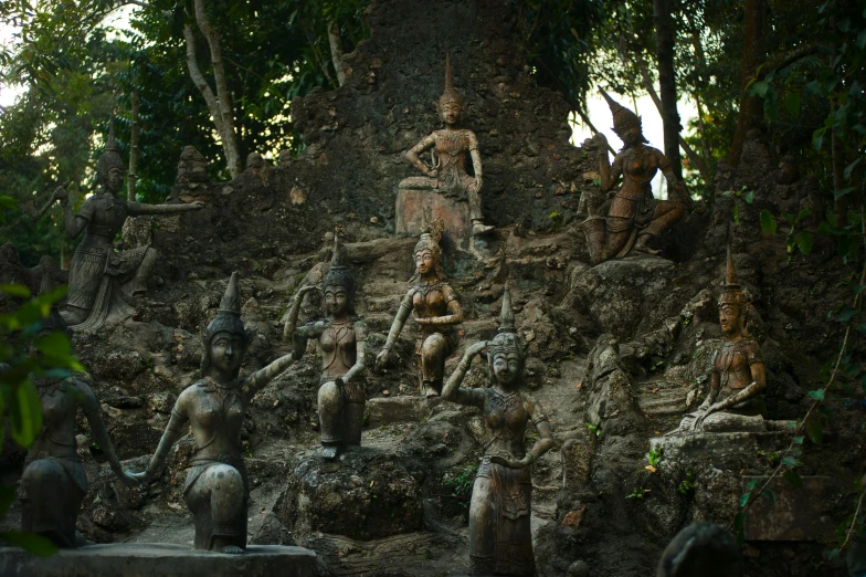 a group of statues sitting on top of a rocky hill, tree roots, thawan duchanee, terracotta, mixed art