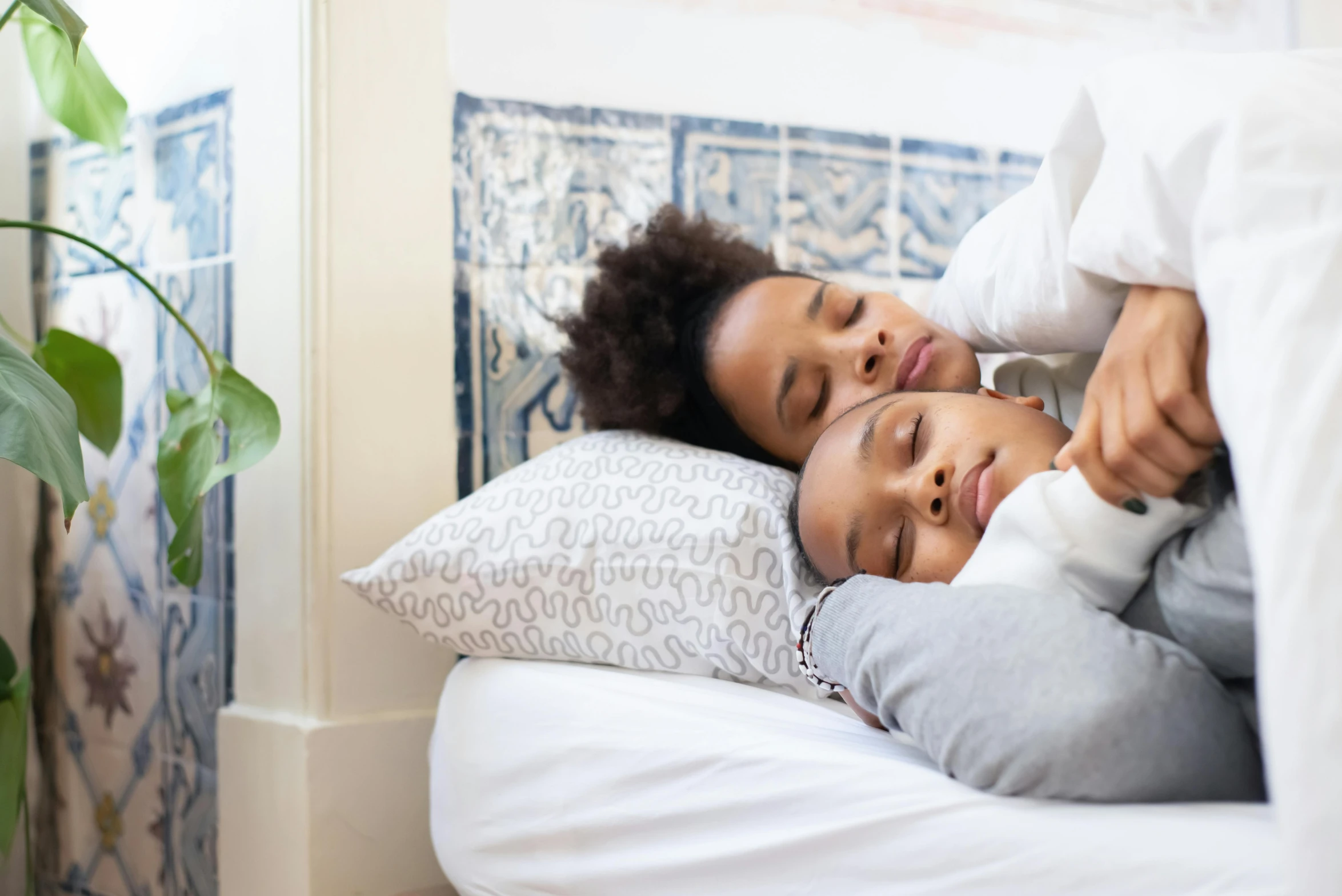 a woman laying on top of a bed next to a child, trending on pexels, essence, grey, adult pair of twins, sleeping