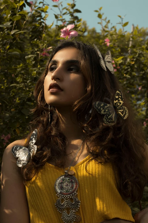 a woman in a yellow dress posing for a picture, an album cover, inspired by irakli nadar, trending on pexels, butterfly jewelry, hindu aesthetic, backlit portrait, innocent look