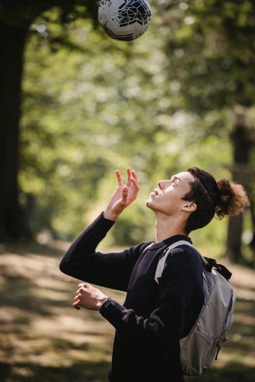 a woman tossing a soccer ball in the air, trending on unsplash, renaissance, a man wearing a backpack, praying posture, in the park, androgynous person