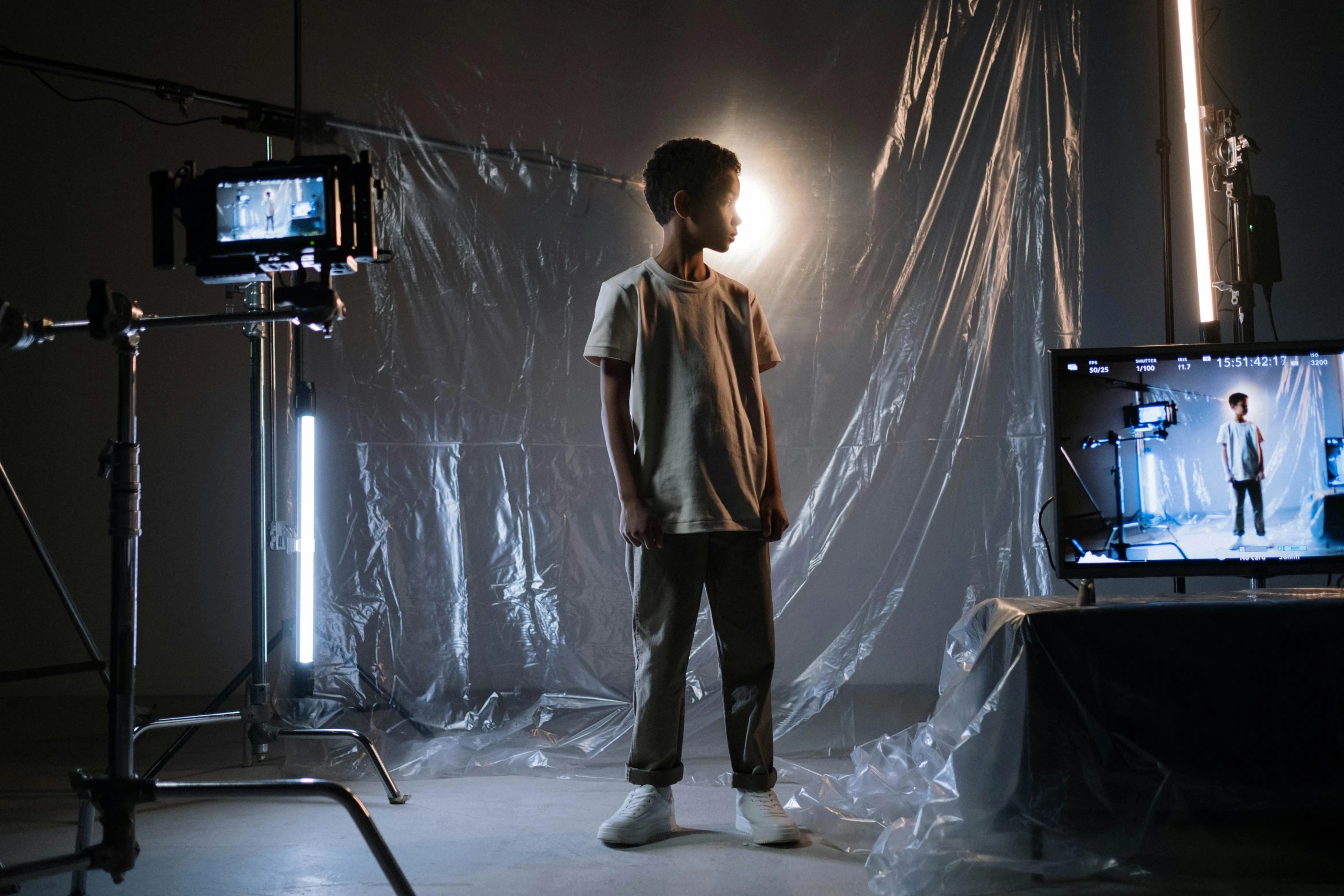 a young boy standing in front of a television, pexels contest winner, video art, fashion studio lighting, on set, worksafe. cinematic, production ig
