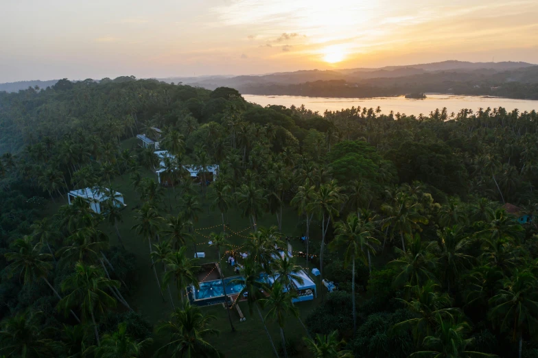 an aerial view of a resort surrounded by palm trees, hurufiyya, large twin sunset, waneella, behind the scenes, glamping