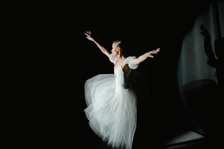 a woman in a white dress standing on a stage, by Elizabeth Polunin, pexels contest winner, arabesque, with a black background, kirsi salonen, wearing a tutu, 15081959 21121991 01012000 4k