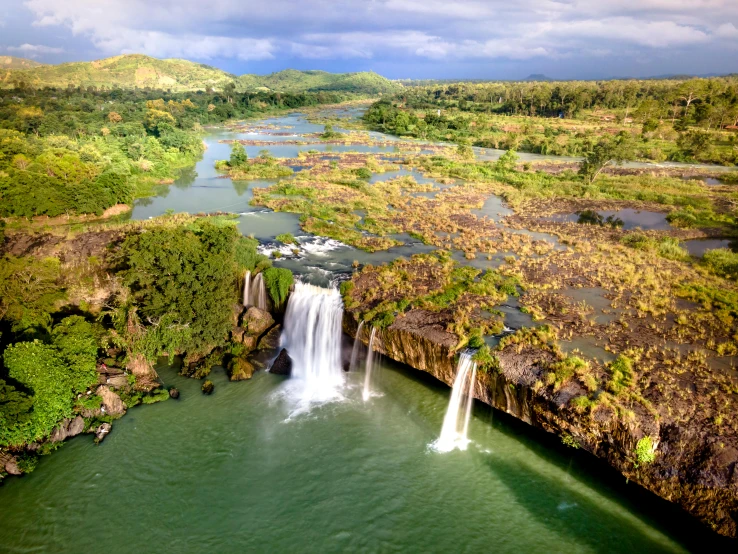 a waterfall in the middle of a large body of water, hurufiyya, arial shot, fan favorite, waneella, waterfalls in distance