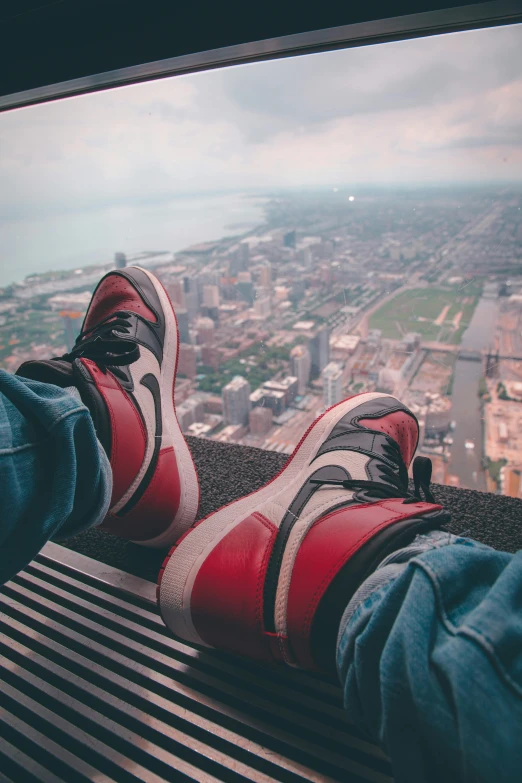 a person sitting on a bench with their feet up, a picture, inspired by Jordan Grimmer, trending on pexels, cn tower, air jordan 1 high, sitting in a crane, red wings