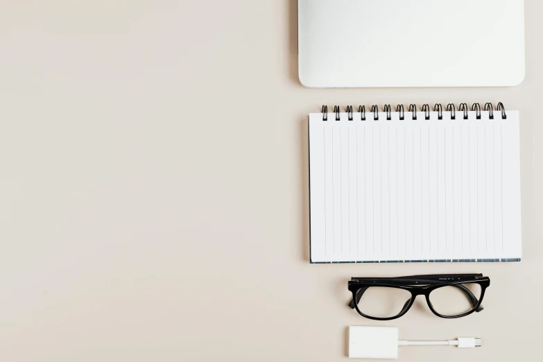 a laptop computer sitting on top of a desk next to a pair of glasses, trending on pexels, minimalism, beige color scheme, pencil and paper, background image, square rimmed glasses