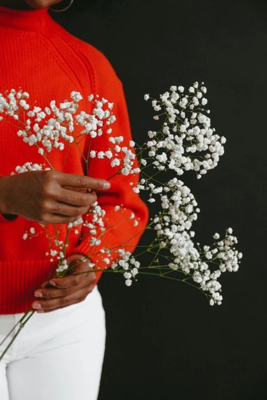 a woman in a red sweater holding a bouquet of flowers, inspired by Elsa Bleda, visual art, gypsophila, ikebana white flowers, orange and white color scheme, pops of color