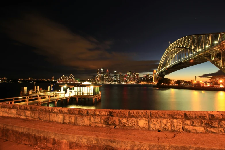 a bridge over a body of water at night, a picture, inspired by Sydney Carline, pexels contest winner, hurufiyya, harbour, full frame image, all buildings on bridge, 8k resolution”