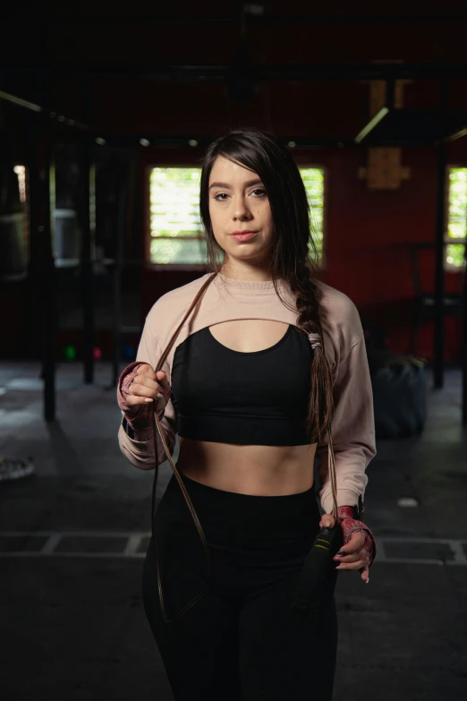 a woman holding a rope in a dark room, by Alejandro Obregón, background a gym, avatar image, 21 years old, headshot photo