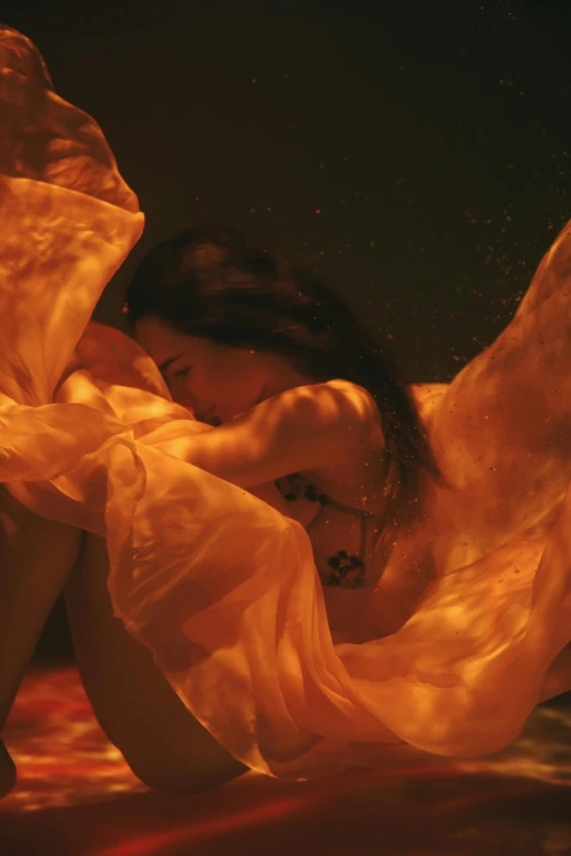 a woman in a yellow dress laying on a bed, an album cover, inspired by Elsa Bleda, engulfed in swirling flames, draped in transparent cloth, lu ji, close - shot