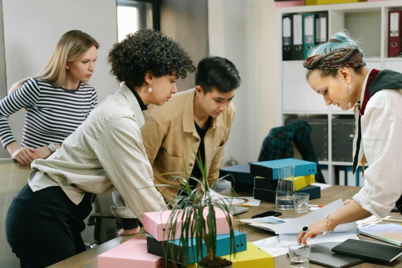 a group of people standing around a table, trending on pexels, sitting on a desk, avatar image, profile image