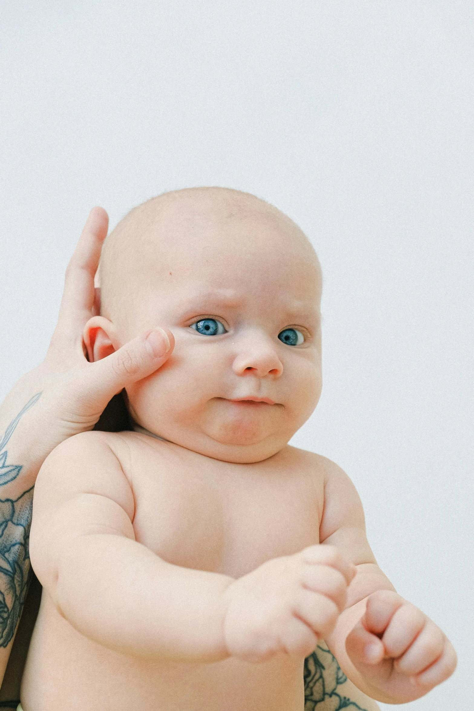 a woman holding a baby in her arms, an album cover, by Gavin Hamilton, trending on reddit, small nose with freckles, giving the middle finger, medical photography, greeting hand on head