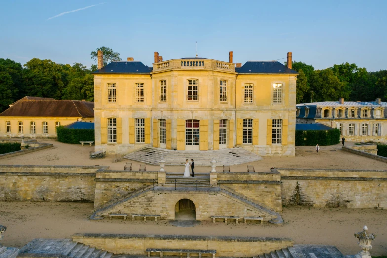 a large yellow building sitting on top of a lush green field, an album cover, inspired by Pierre Mion, pexels contest winner, rococo, wide grand staircase, evening light, normandy, symmetrical front view