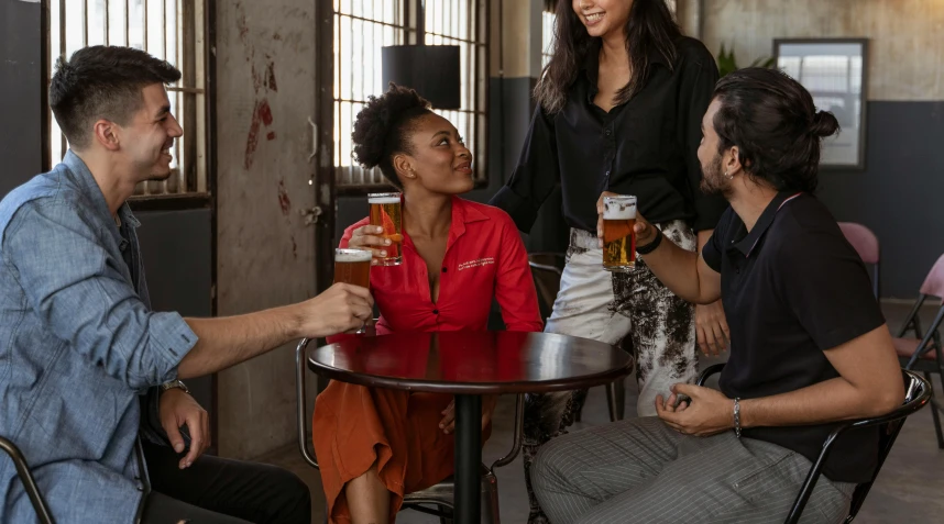 a group of people sitting around a table drinking beer, curated collections, red shirt brown pants, female model, aussie baristas