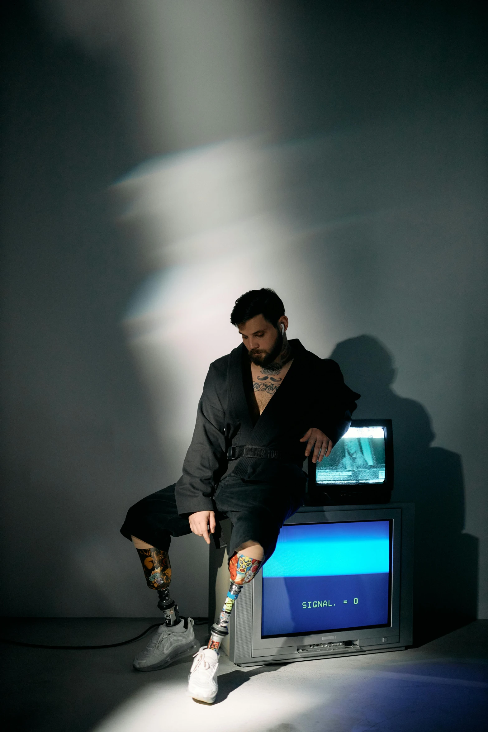 a man sitting on top of a television set, an album cover, inspired by Carlo Mense, unsplash, massurrealism, prosthetic leg, bam margera, zachary quinto, shot in the photo studio