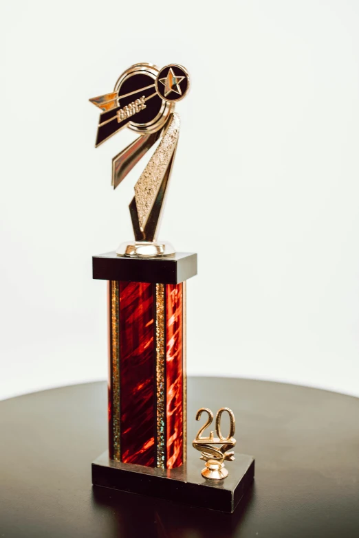 a trophy sitting on top of a wooden table, '20, award winning color photo, gold and red metal, 2 0