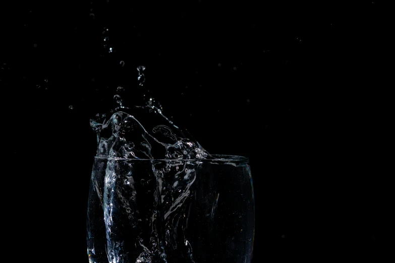 a glass filled with water sitting on top of a table, an album cover, pexels, photorealism, black background pinterest, water sprites, excitement, ignant