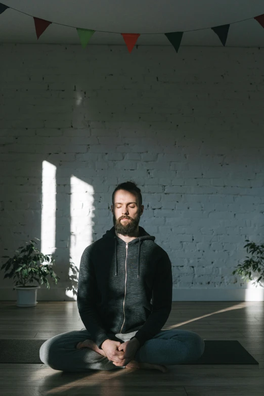 a man sitting on a yoga mat in the middle of a room, a character portrait, by Attila Meszlenyi, light and space, low quality photo, lachlan bailey, front facing, profile image