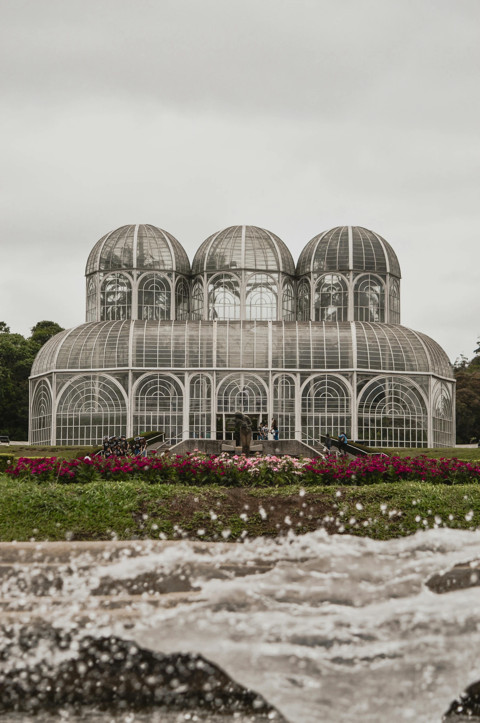 a large building sitting on top of a lush green field, by Christo, unsplash contest winner, art nouveau, water flows inside the terrarium, orchids, buenos aires, overcast weather