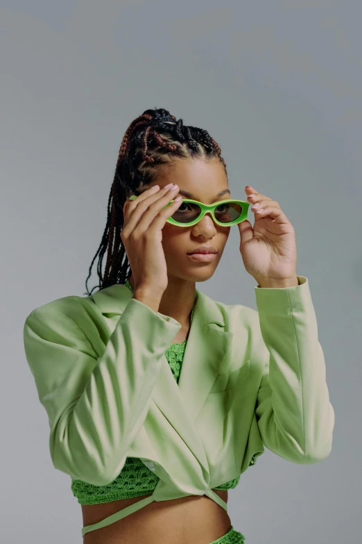 a woman in a green suit and sunglasses, trending on pexels, renaissance, willow smith zendaya, riyahd cassiem, solid background, small square glasses