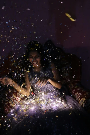 a woman sitting on top of a bed covered in confetti, pexels contest winner, holography, bollywood, at a birthday party, photographed for reuters, taken in the late 2010s