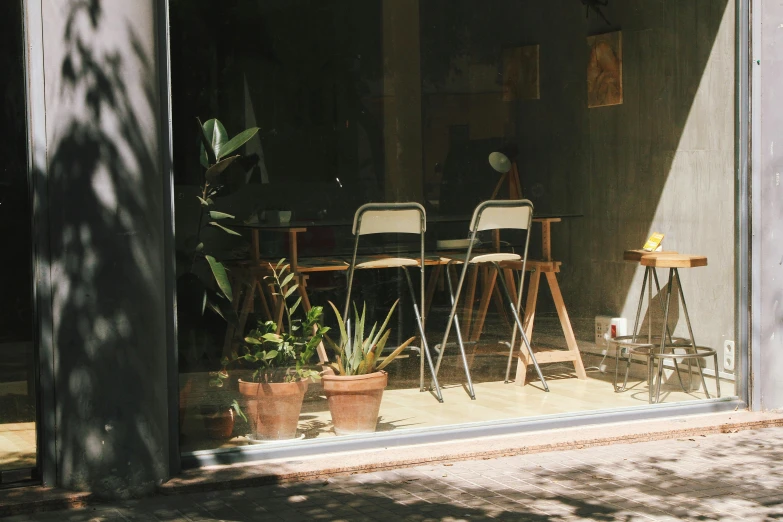 a couple of chairs sitting in front of a window, pexels contest winner, light and space, small hipster coffee shop, plants and patio, exiting store, in barcelona