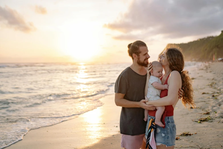 a man and woman holding a baby on a beach, pexels contest winner, avatar image, morning lighting, 1 4 9 3