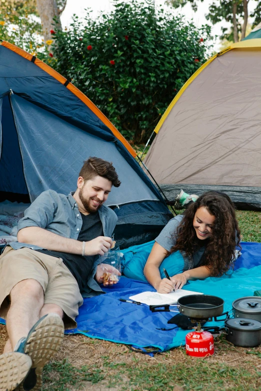 a couple of people that are sitting in the grass, tents, planning, lachlan bailey, outdoors setting