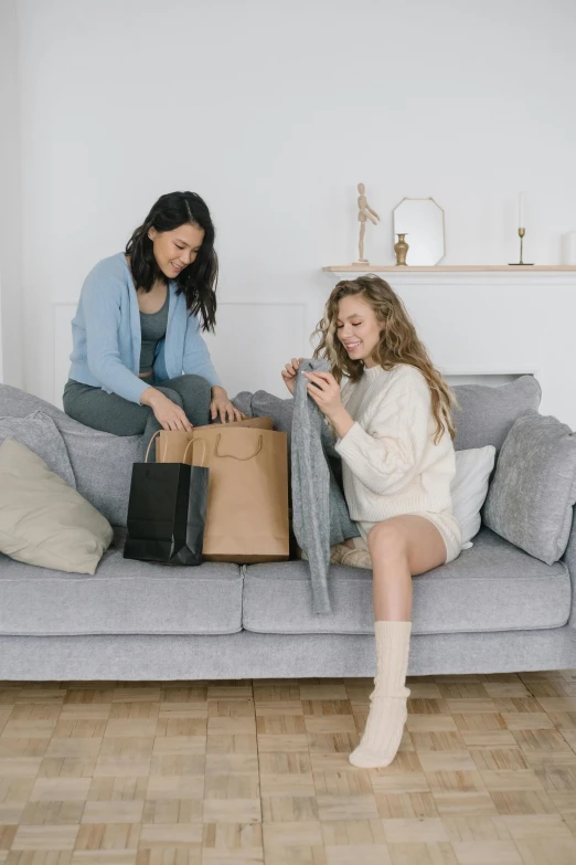 a woman sitting on top of a couch next to a little girl, by Adam Saks, trending on pexels, happening, shopping groceries, neutral colours, avatar image, bags