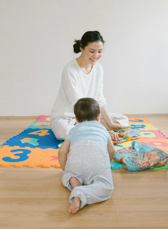 a woman sitting on the floor playing with a baby, shin hanga, profile image