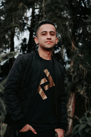 a man standing with his hands in his pockets, inspired by Alejandro Obregón, featured on reddit, wearing a black sweater, against the backdrop of trees, furaffinity, discord profile picture