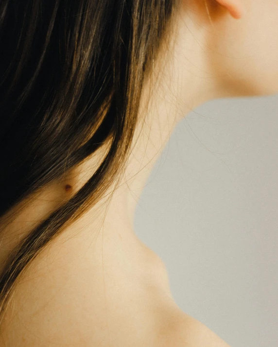 a woman with a flower in her hair, inspired by Ren Hang, trending on pexels, mingei, showing her shoulder from back, cleft chin, brunette woman, dark. no text