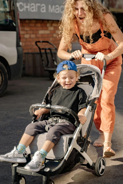 a woman pushing a child in a stroller, a portrait, by Drew Tucker, pexels contest winner, young boy, thumbnail, enhanced quality, full product shot