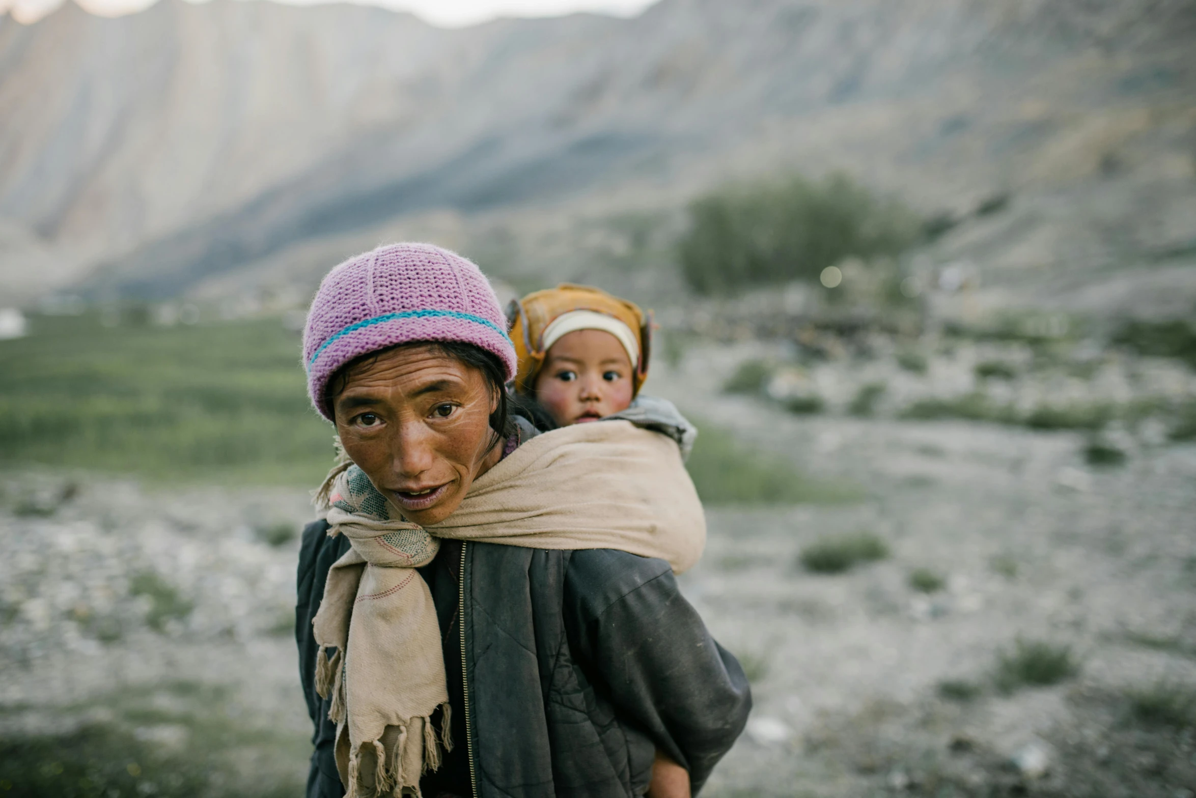 a man carrying a child on his back, inspired by Steve McCurry, unsplash contest winner, hurufiyya, in a mountain valley, hasselblad photo, asian face, multicoloured