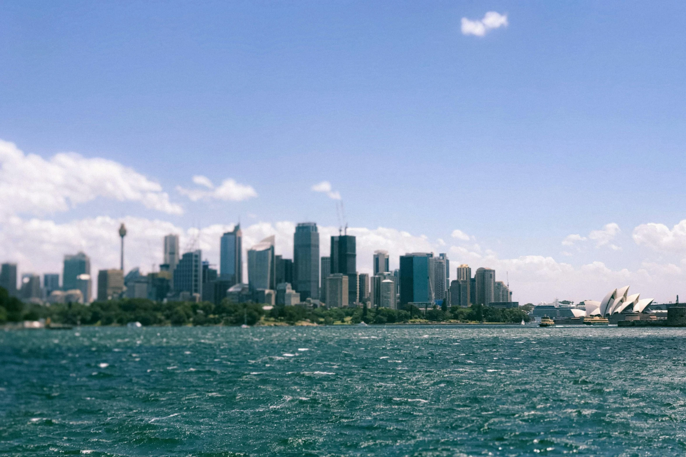 a large body of water with a city in the background, inspired by Sydney Carline, pexels contest winner, hurufiyya, clear blue sky, overexposed photograph, 2000s photo, view from the sea