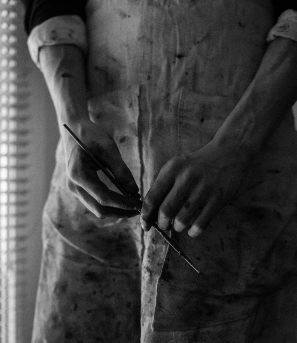 a black and white photo of a person holding a pair of scissors, by Emma Andijewska, process art, hard clay, butcher, tailored clothing, closeup of a butcher working