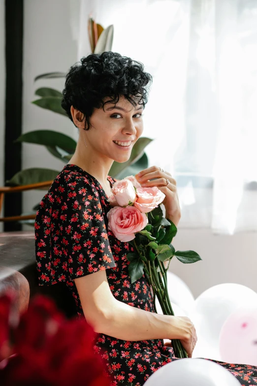 a woman sitting on a couch holding a bunch of flowers, curly pixie cut hair, rebecca sugar, roses, with black hair