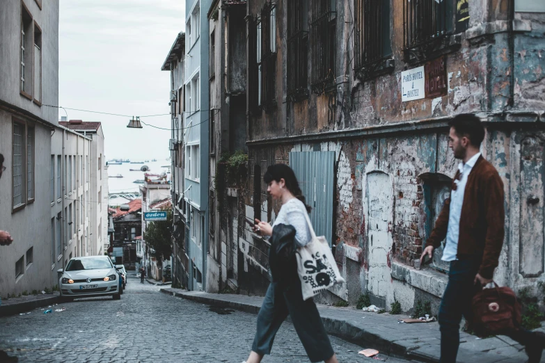 a couple of people that are walking down a street, pexels contest winner, fallout style istanbul, built on a steep hill, woman in streetwear, conde nast traveler photo