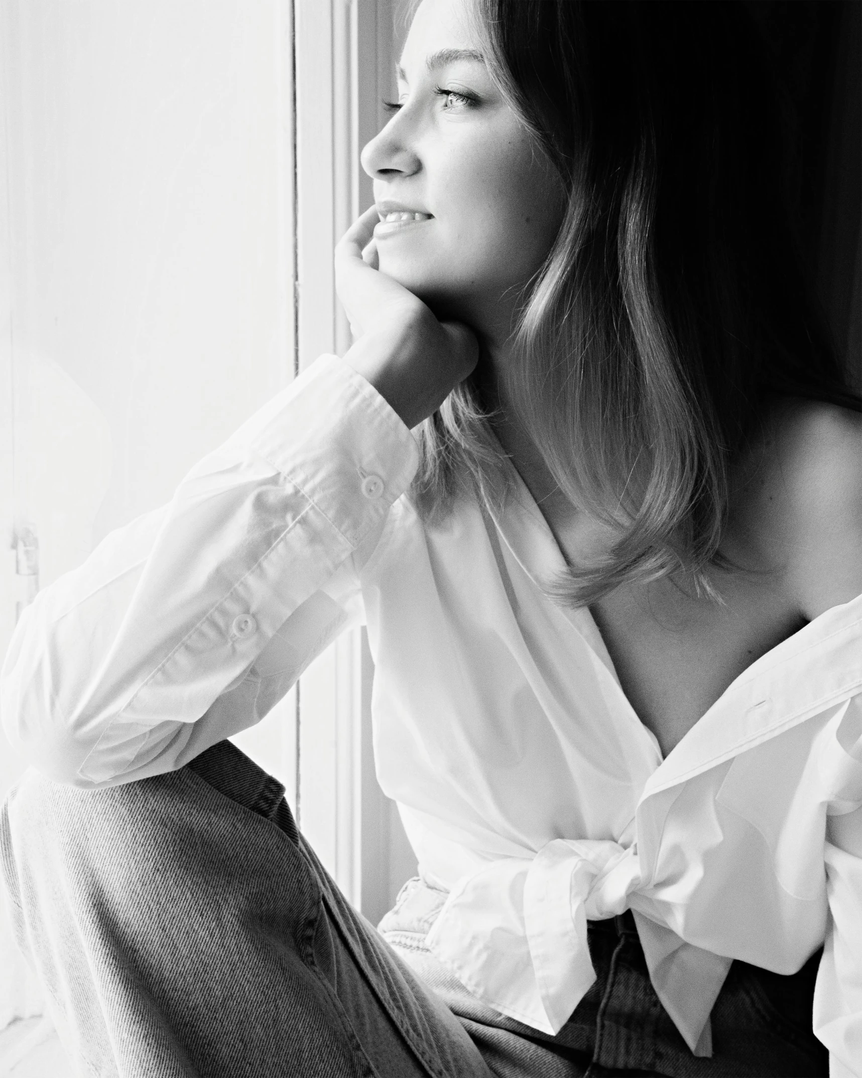 a black and white photo of a woman sitting on a window sill, wearing a white blouse, jessica alba woman, monochrome:-2, caroline gariba