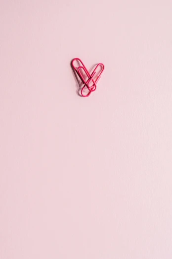 a paper clip in the shape of a heart on a pink background, by Jacob Toorenvliet, pexels contest winner, ffffound, vertical wallpaper, minimalissimo, kiss