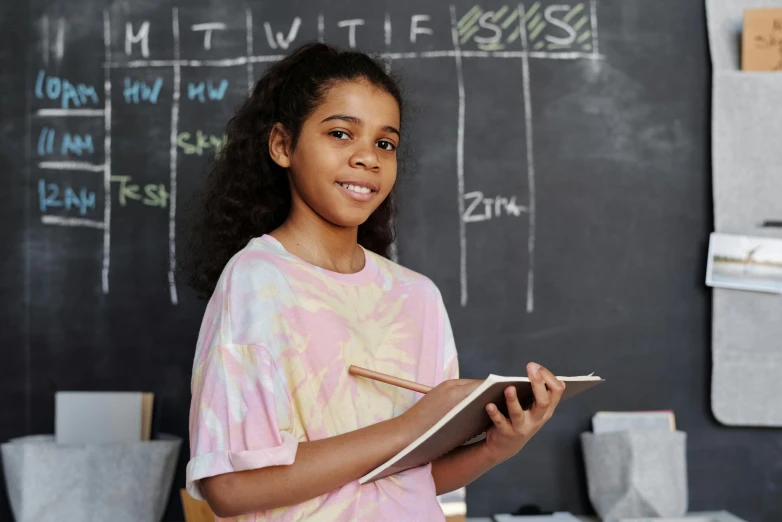 a young girl standing in front of a blackboard, pexels contest winner, ashcan school, holding notebook, ( ( dark skin ) ), 15081959 21121991 01012000 4k, a still of a happy