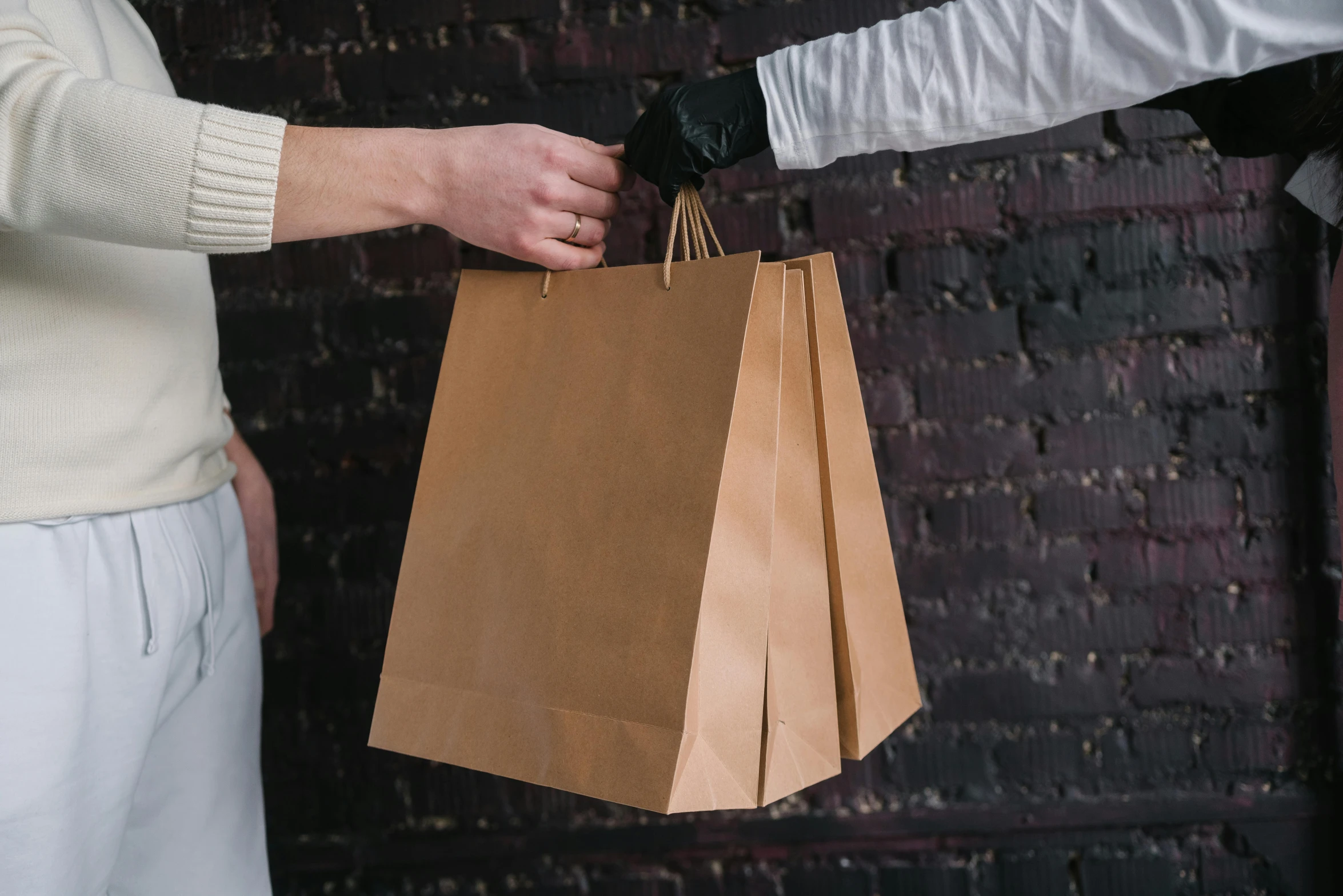 a person handing a brown paper bag to another person, pexels contest winner, private press, white apron, fancy dress, leather clothing, some long