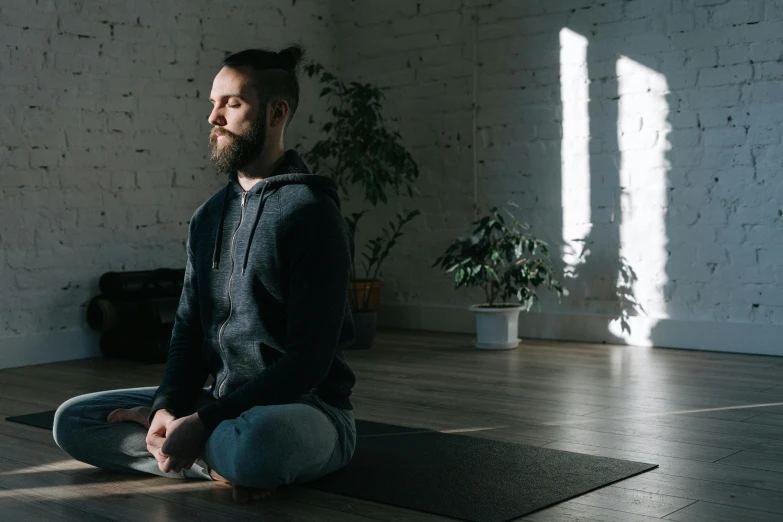 a man sitting on a yoga mat in a room, a portrait, unsplash, background image, profile photo, lachlan bailey, realistic photo