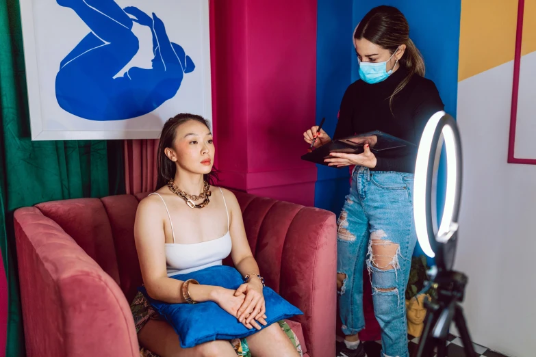 a woman sitting on a couch in front of a mirror, wlop and ross tran, with blue skin, photo booth, on set