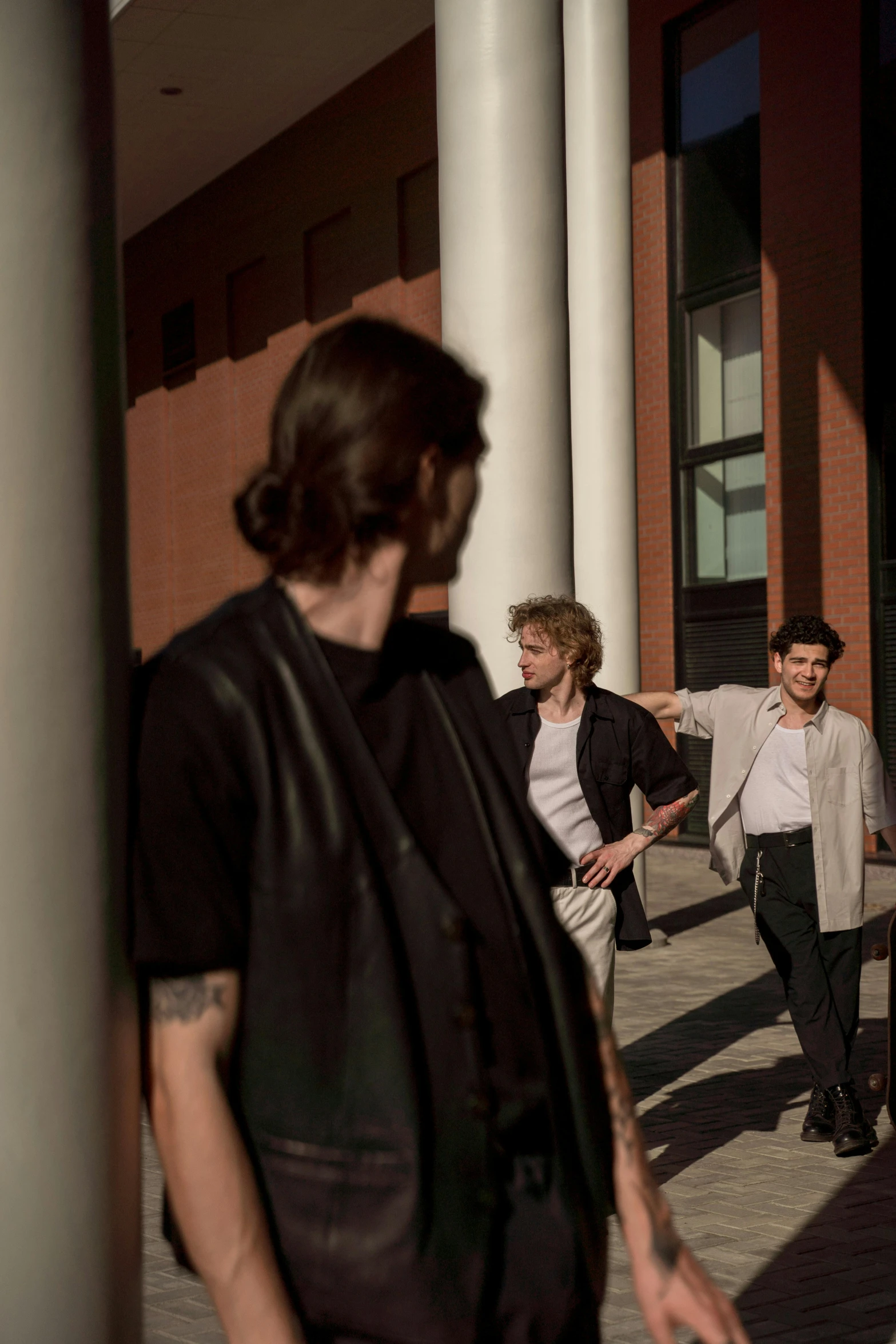 a group of people walking down a sidewalk, an album cover, pexels contest winner, bauhaus, young handsome pale roma, warm glow, holding court, looking around a corner