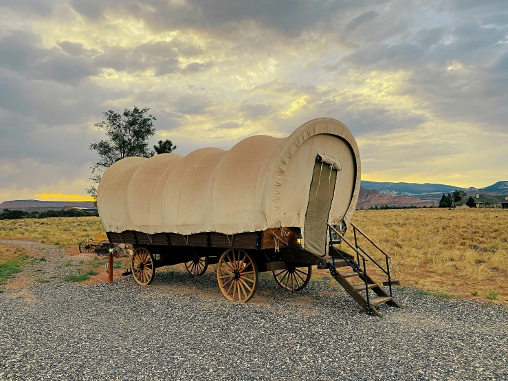 a covered wagon sitting on top of a gravel road, glamping, architectural digest, monument, square