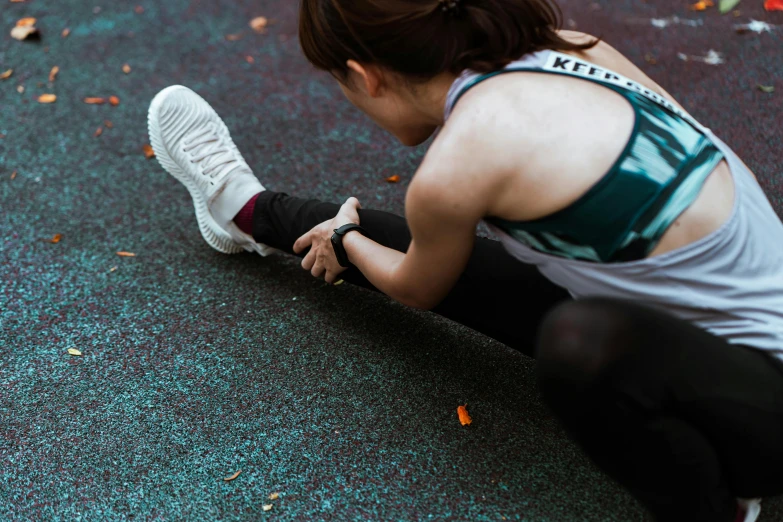 a woman sitting on the ground tying up her shoes, pexels contest winner, sport clothing, pixeled stretching, girl is running, looking down